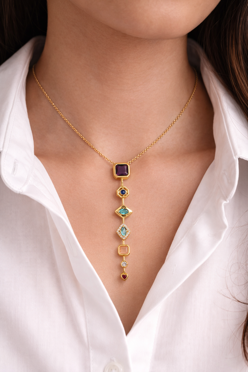 Gold necklace with gemstones worn by a person in a white shirt