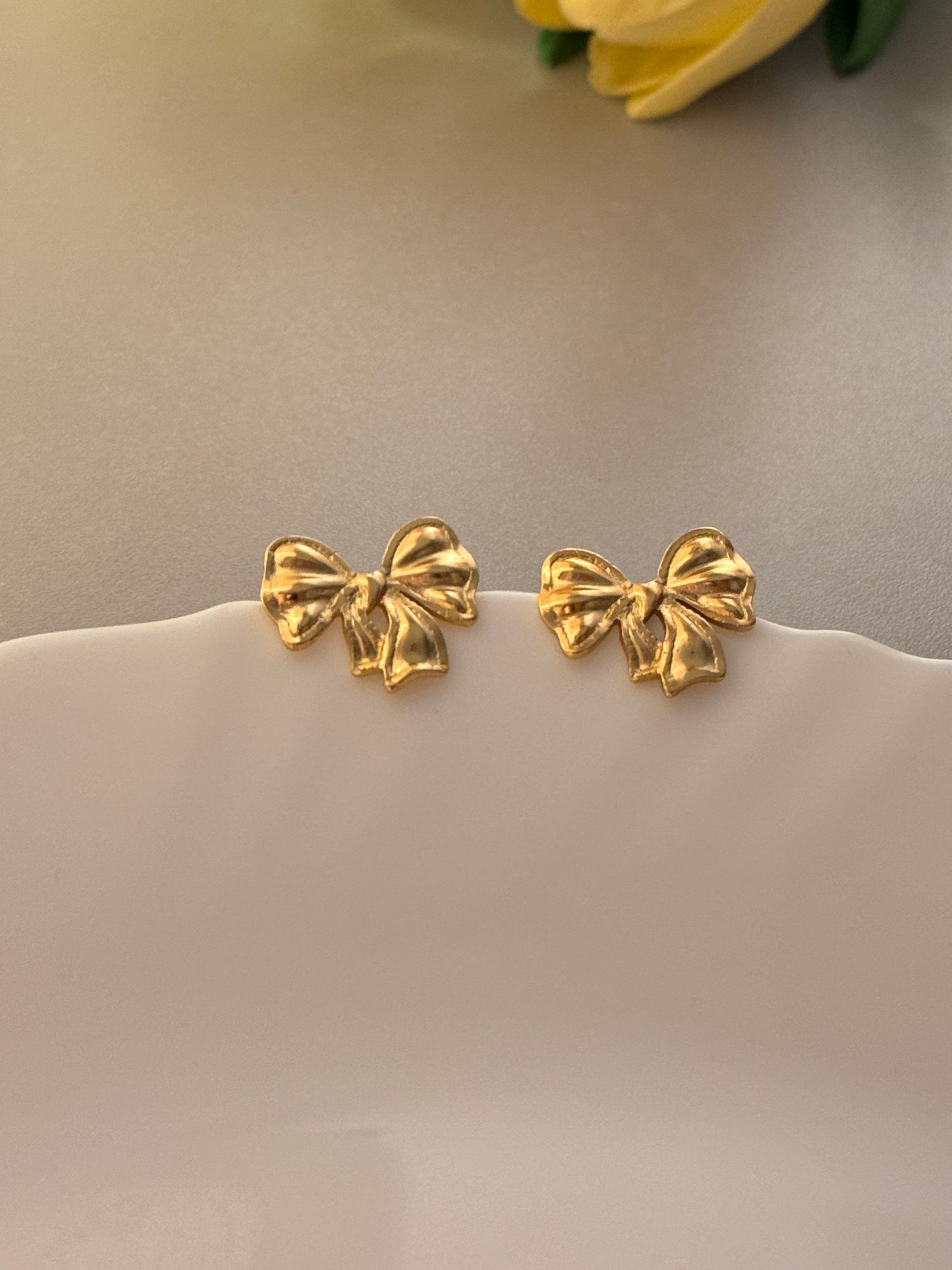 Three gold bow-shaped earrings on a white background