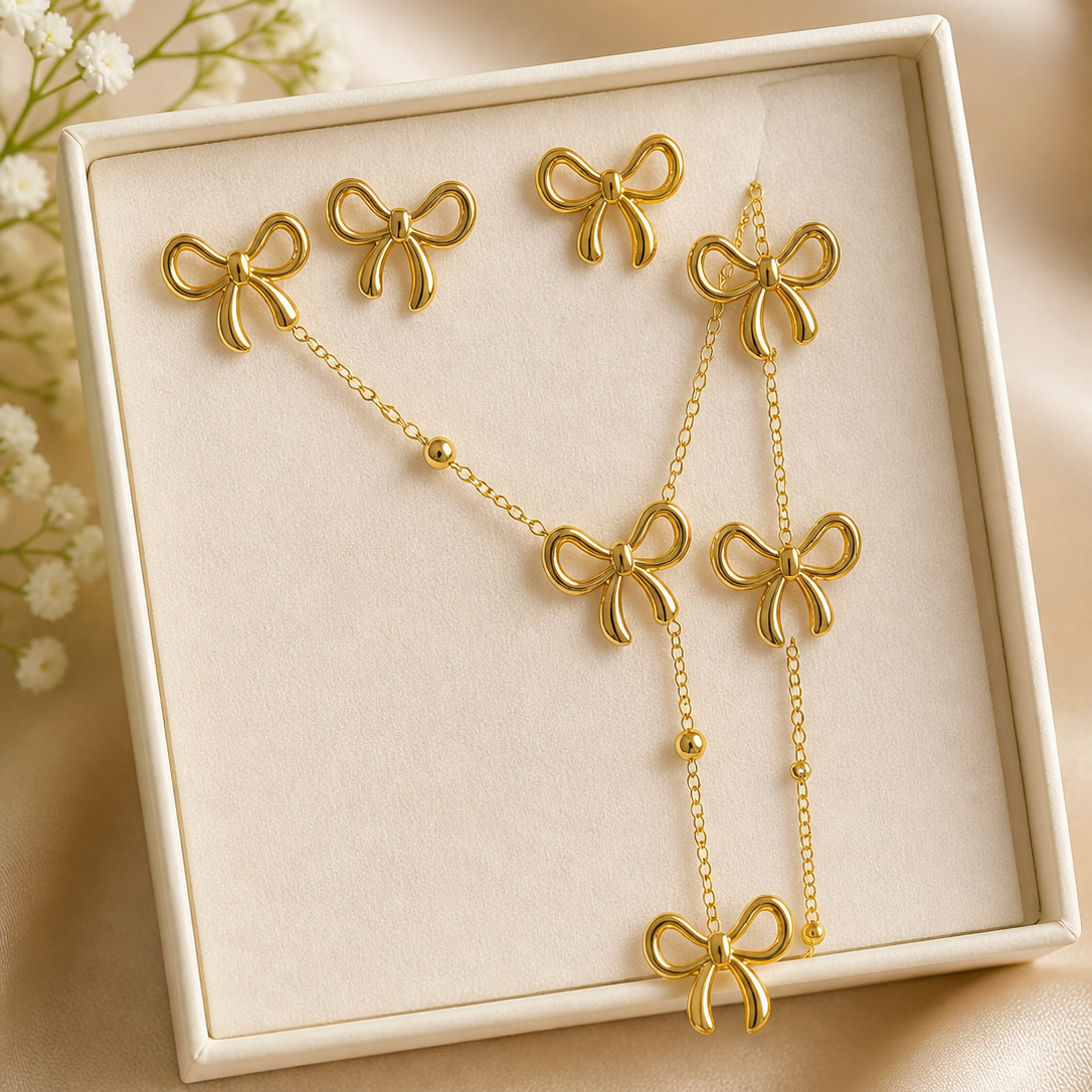 Gold bow-shaped jewelry set in a box with flowers in the background