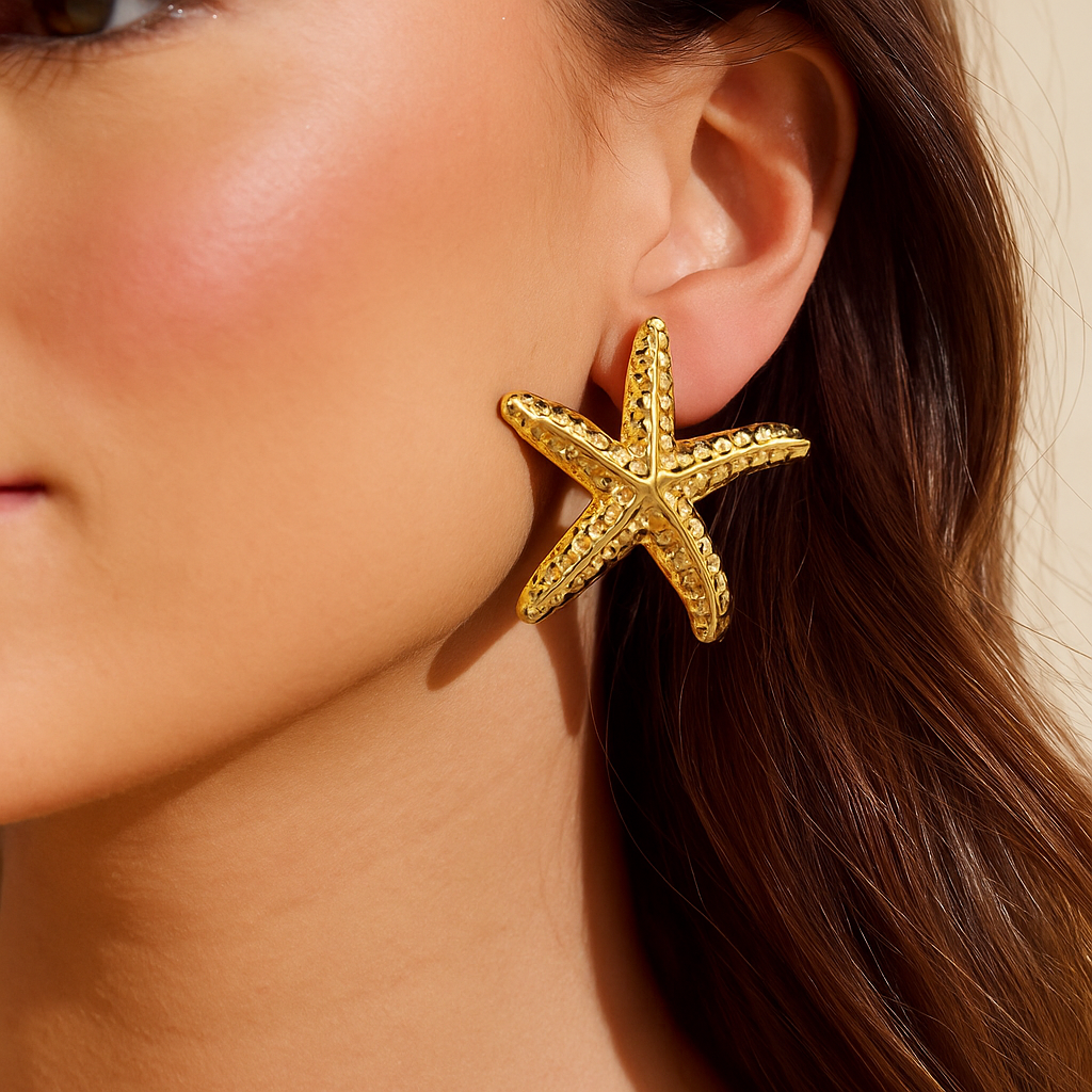 Gold starfish earring worn by a person with a neutral background