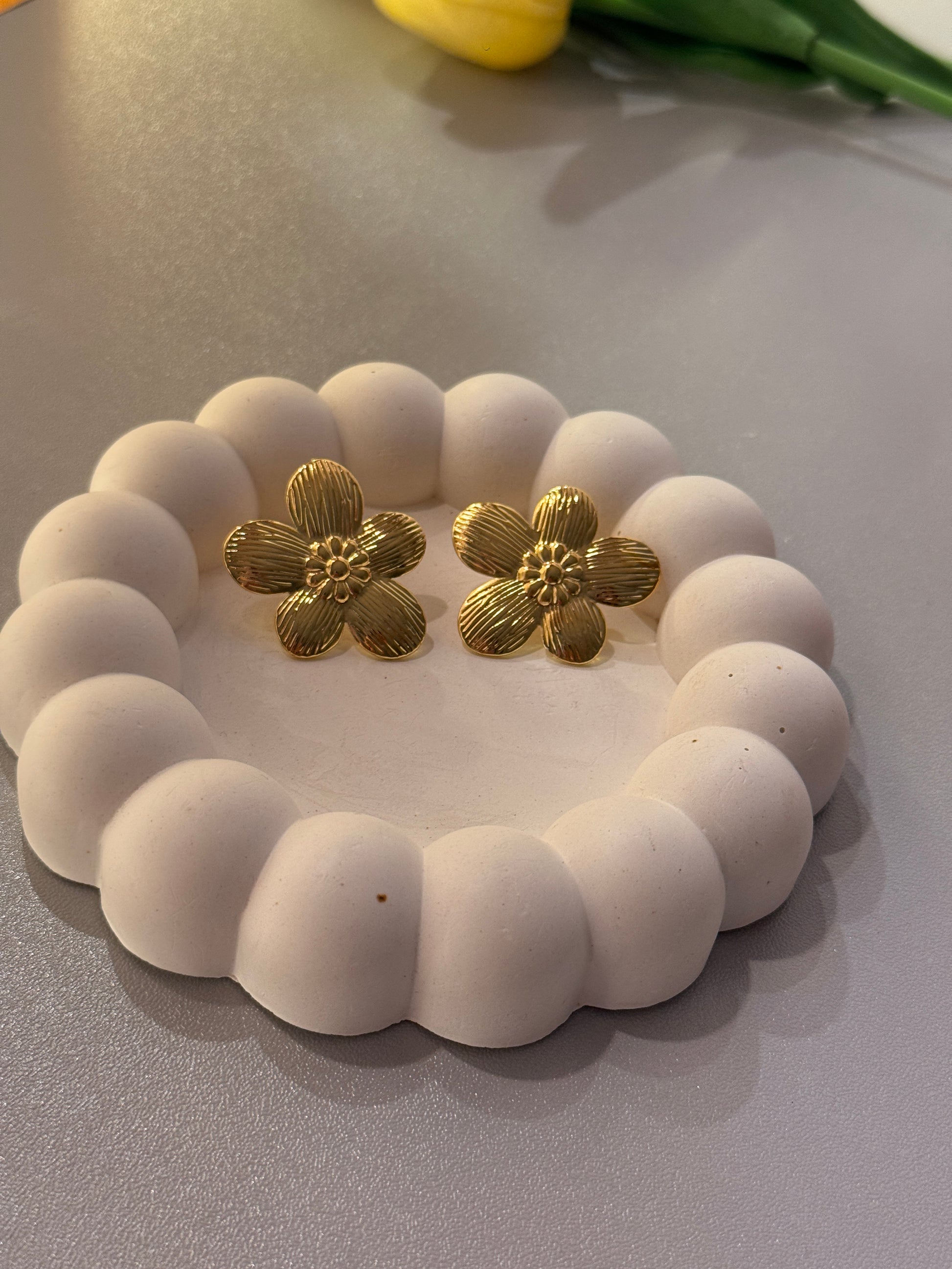 White beaded bracelet with gold flower-shaped beads on a gray surface