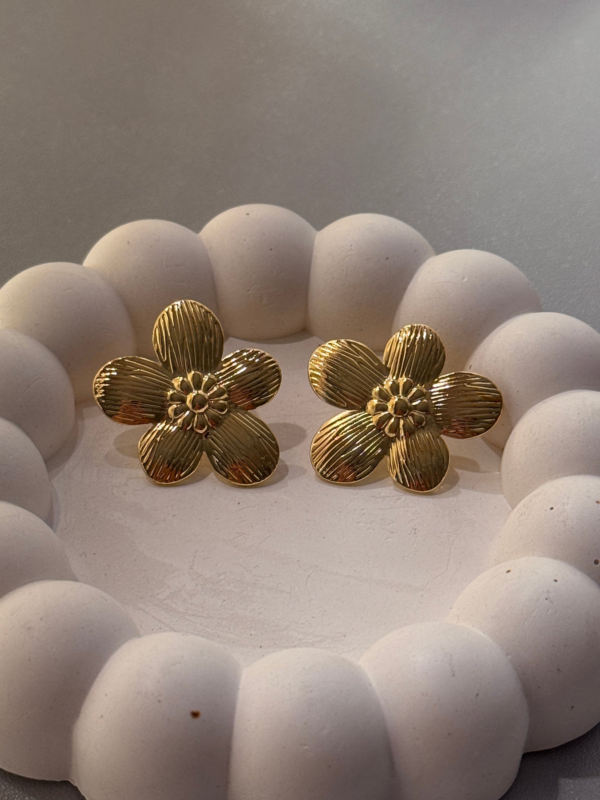White beaded bracelet with gold floral clasps on a neutral background
