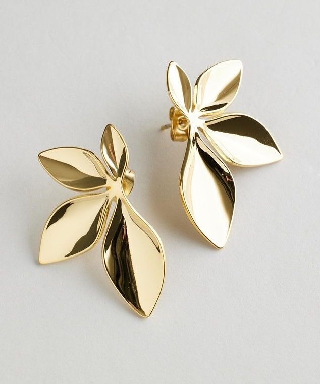 Gold leaf-shaped earrings on a light gray background