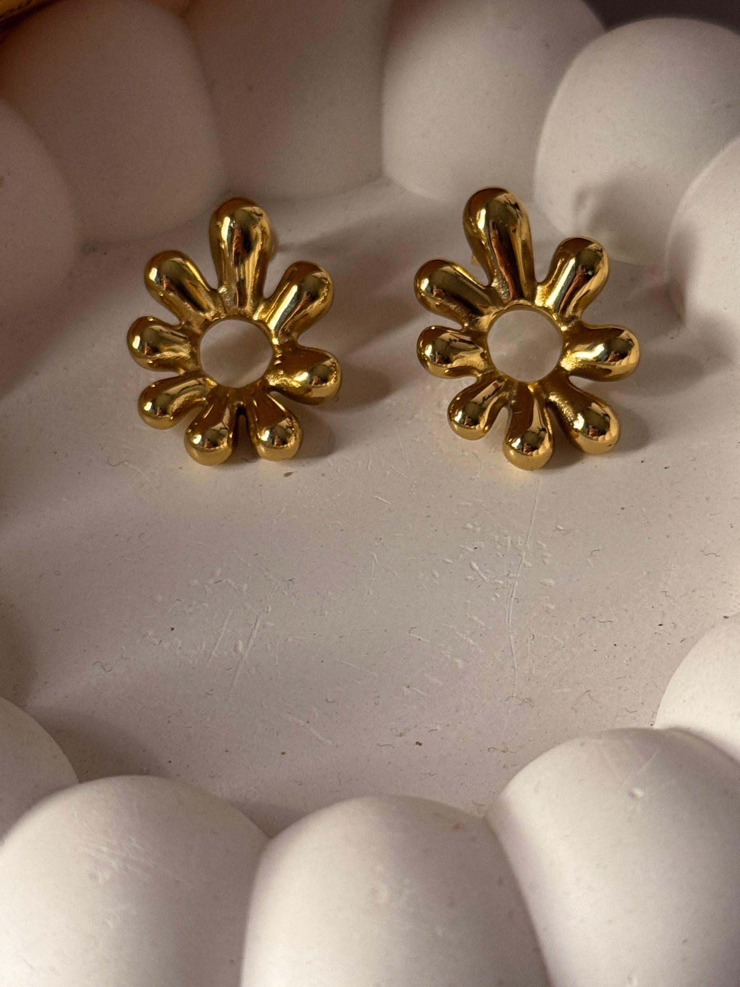 Two gold flower-shaped beads on a white surface