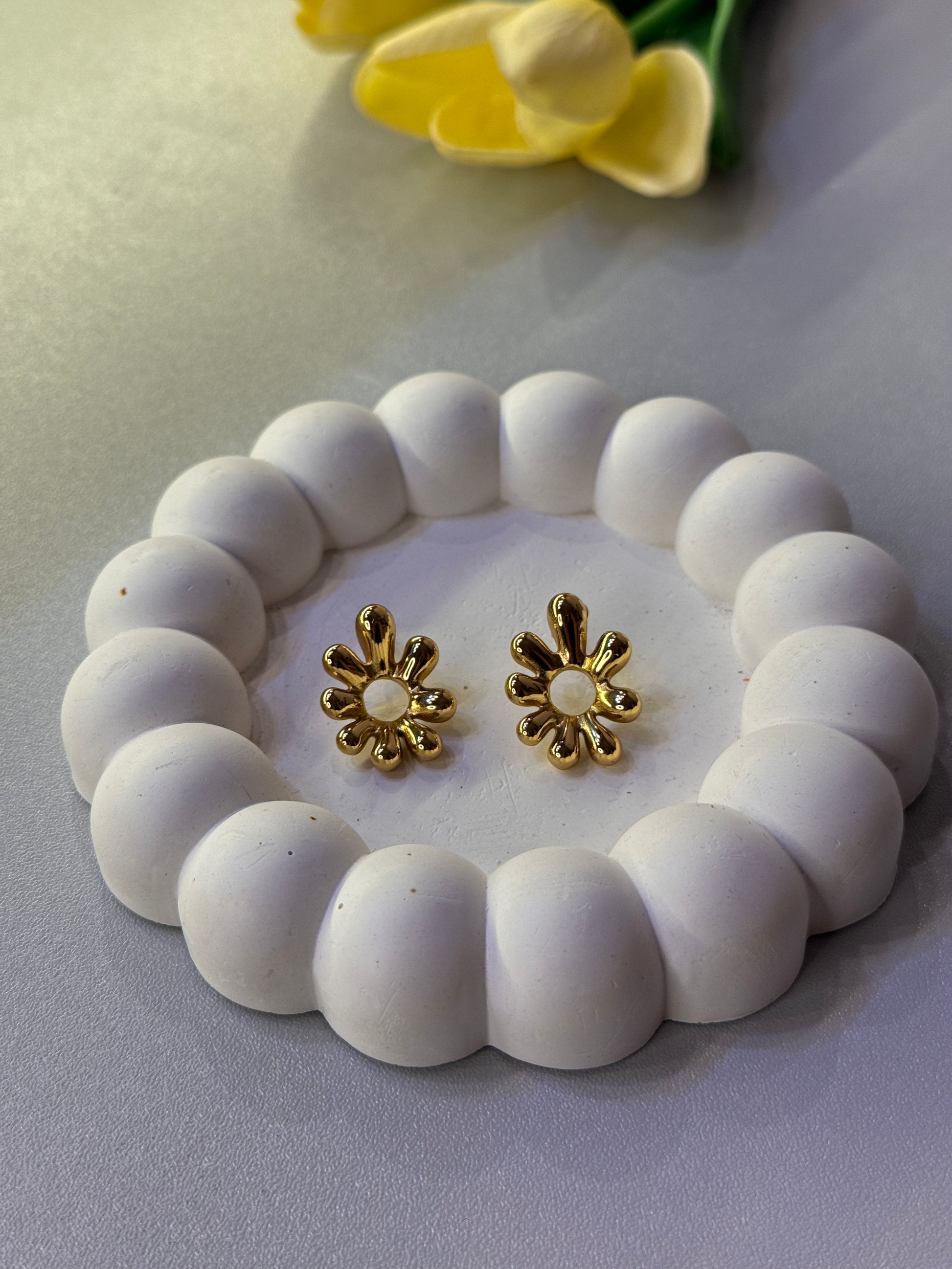 White beaded bracelet with gold flower-shaped clasps on a light gray background