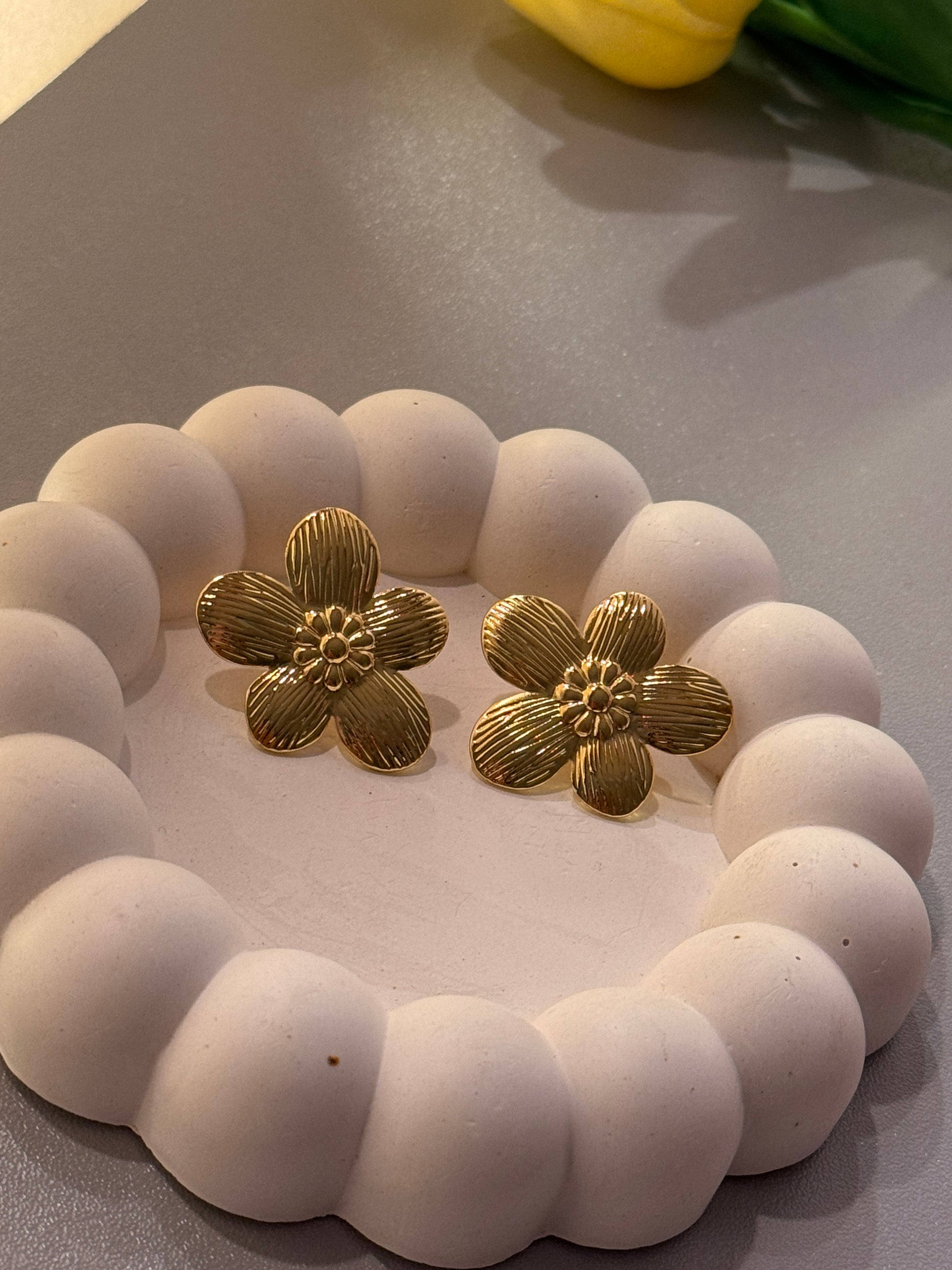 White beaded bracelet with gold flower-shaped clasps on a neutral background