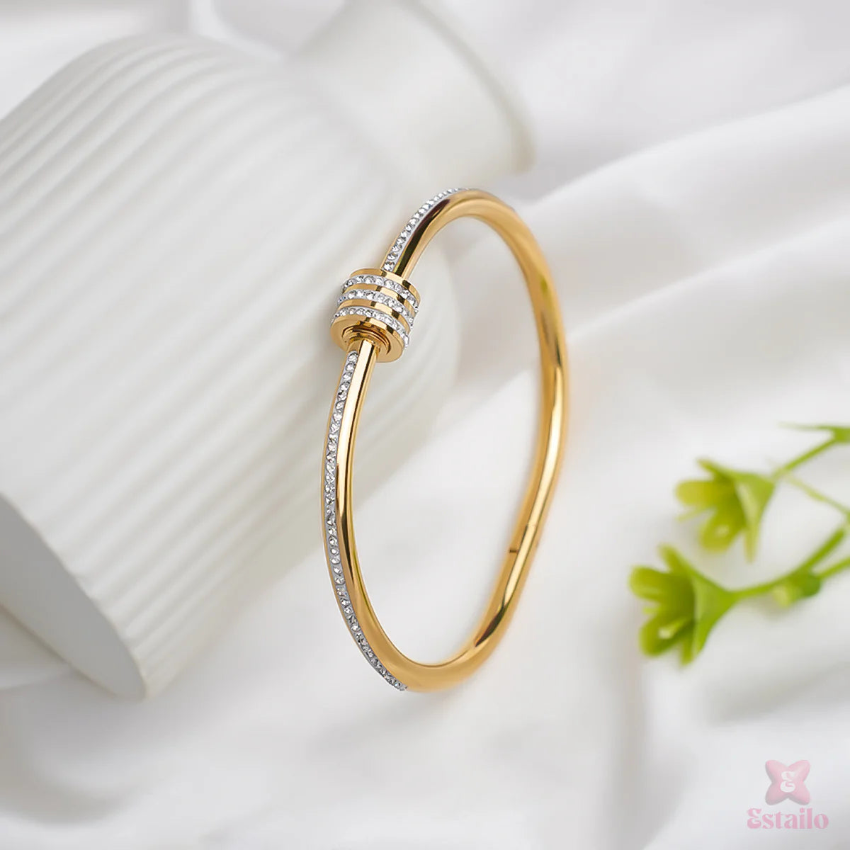 Gold bracelet with diamond accents on a white fabric background