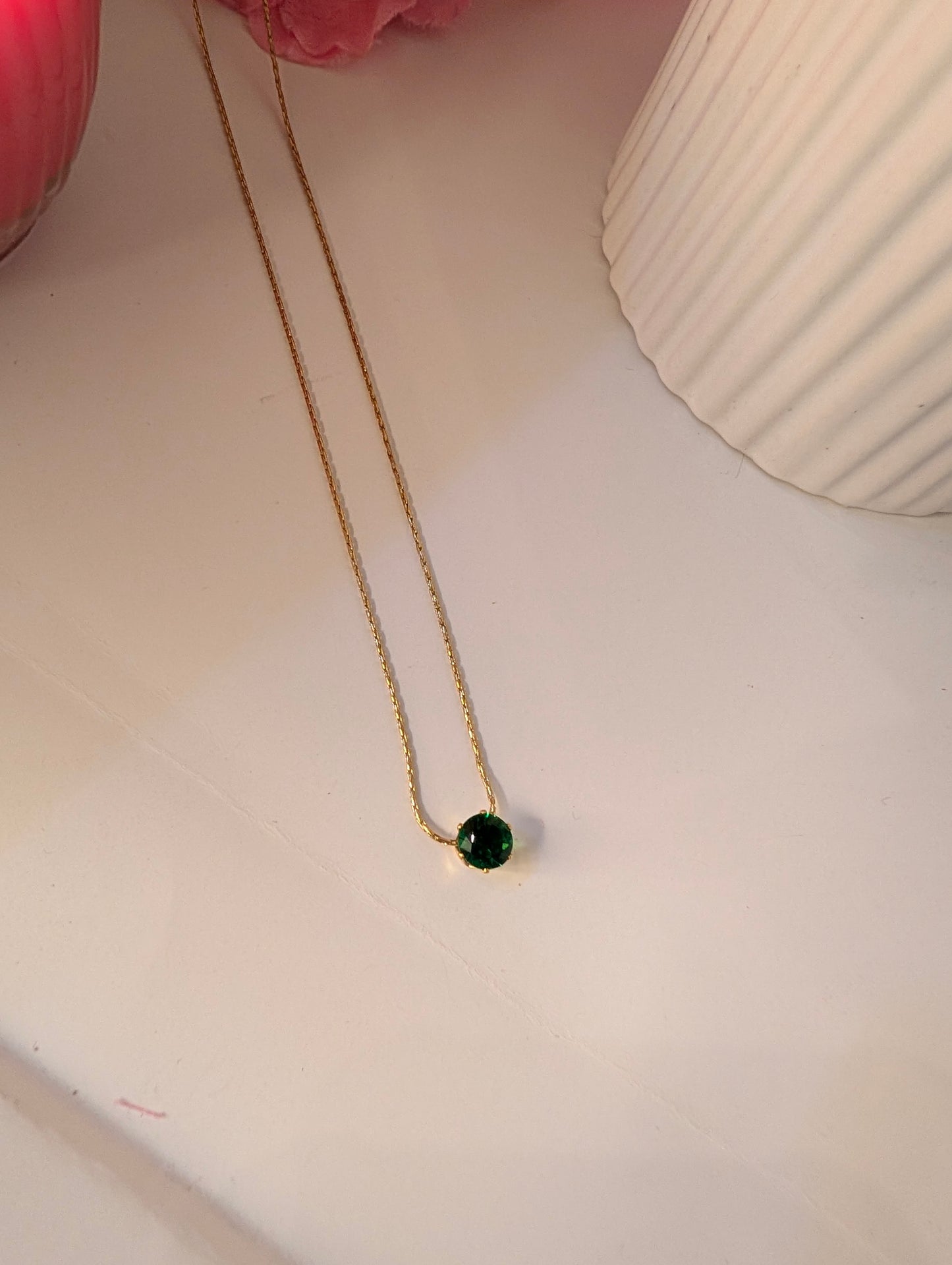 Necklace with a green pendant on a light surface