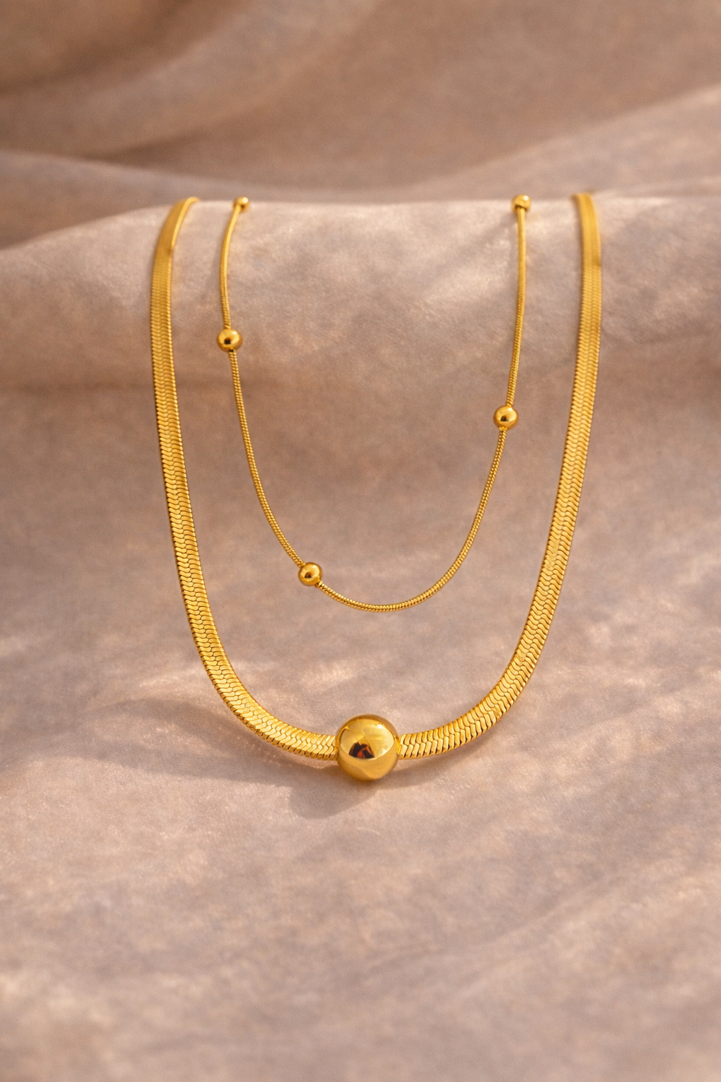 Gold necklace on a textured beige surface