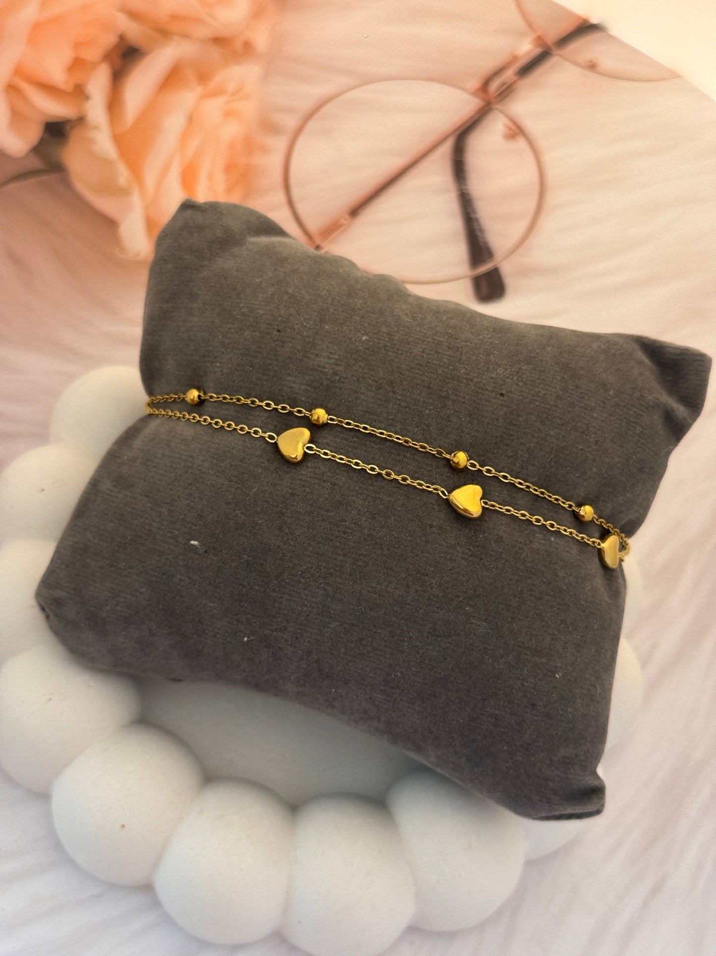 Gold heart-shaped necklace on a gray cushion with a soft background