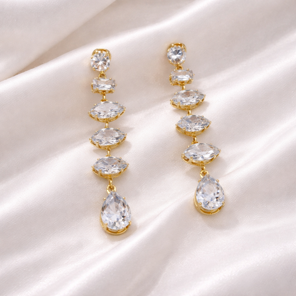 Gold and crystal drop earrings on a satin surface