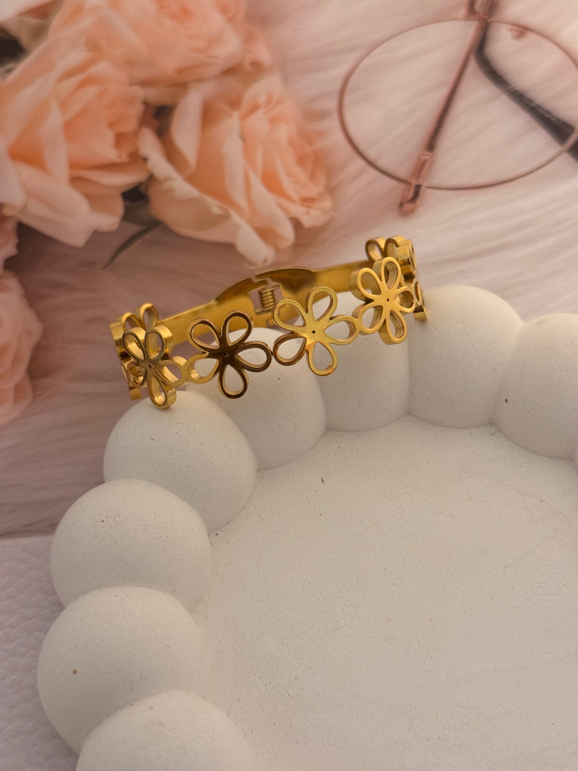 Gold hair clip with floral design on a soft pink background