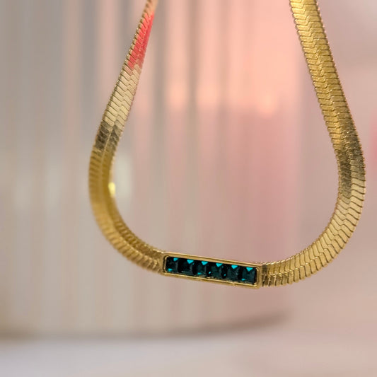 Gold necklace with blue stones on a soft pink background