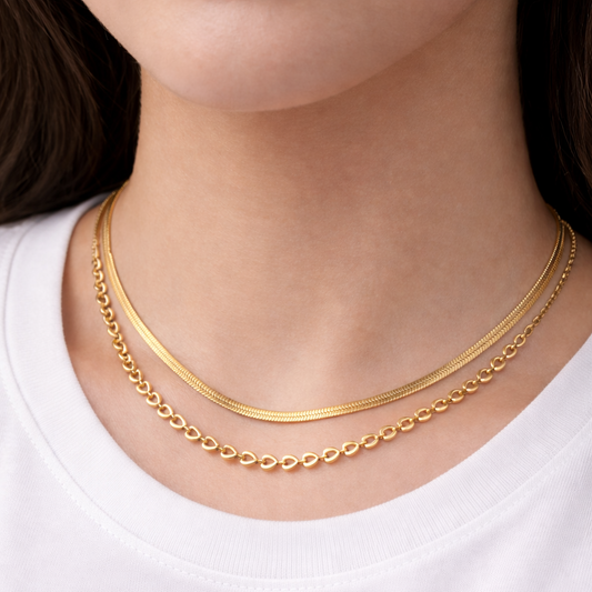 Gold necklace on a person wearing a white shirt