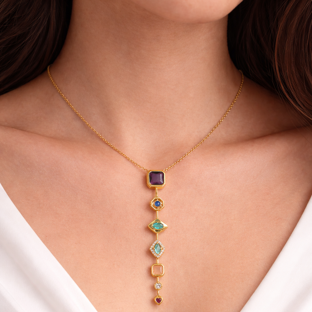 Gold necklace with colorful gemstones worn by a person in a white top