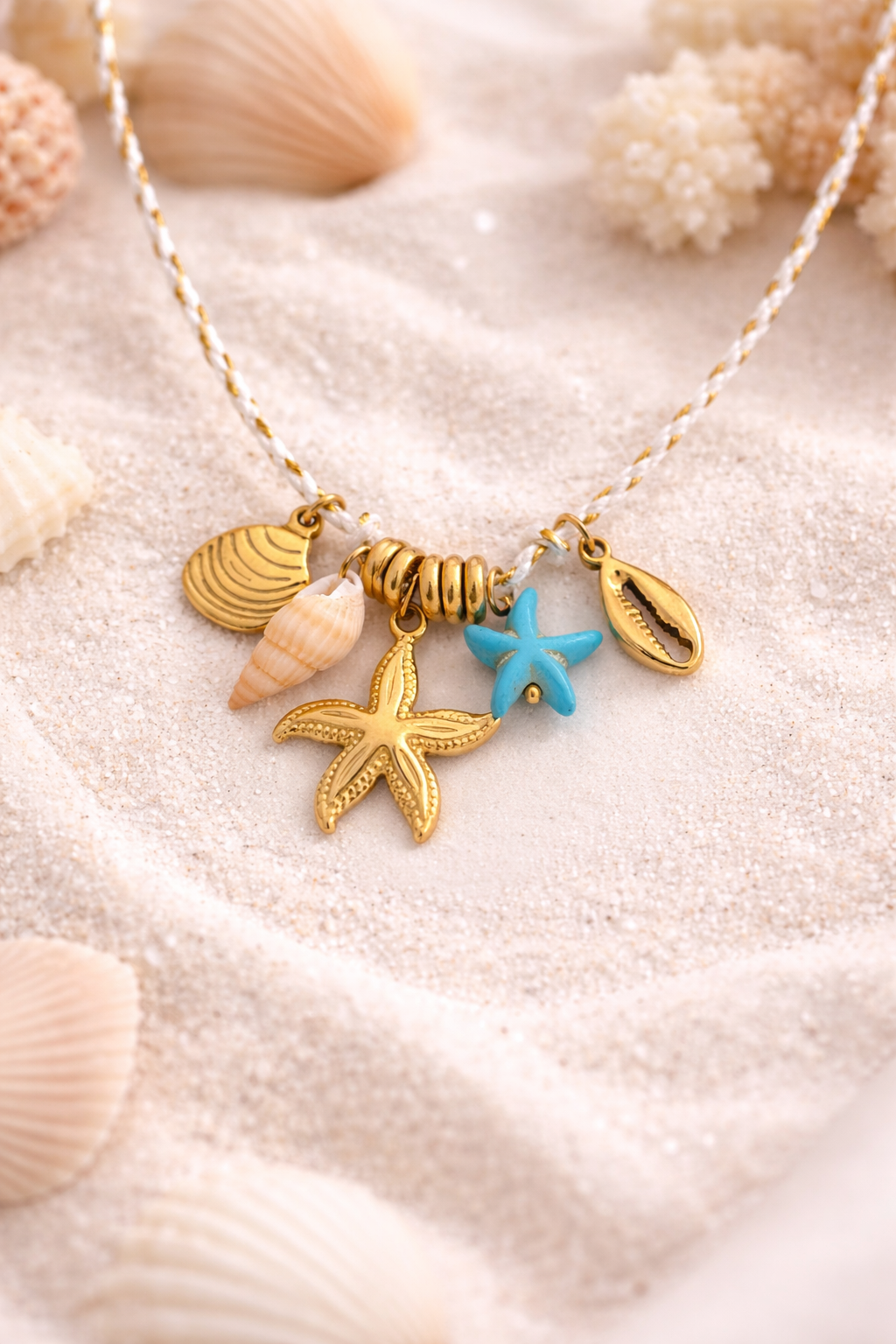 Necklace with shell and starfish charms on a sandy background
