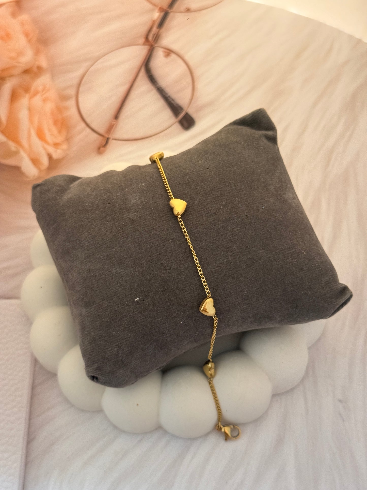 Gold bracelet on a gray cushion with blurred background