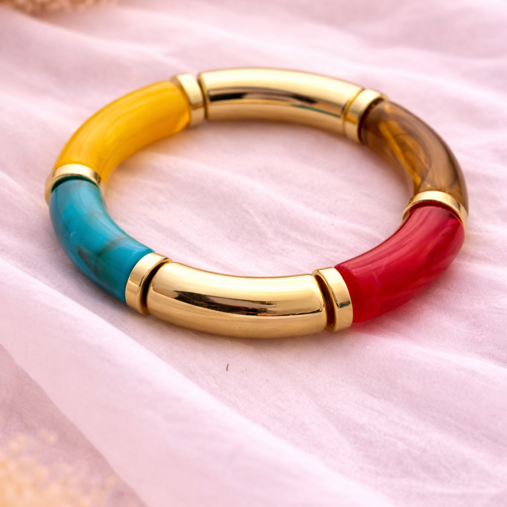 Multicolored bracelet with gold accents on a pink fabric background