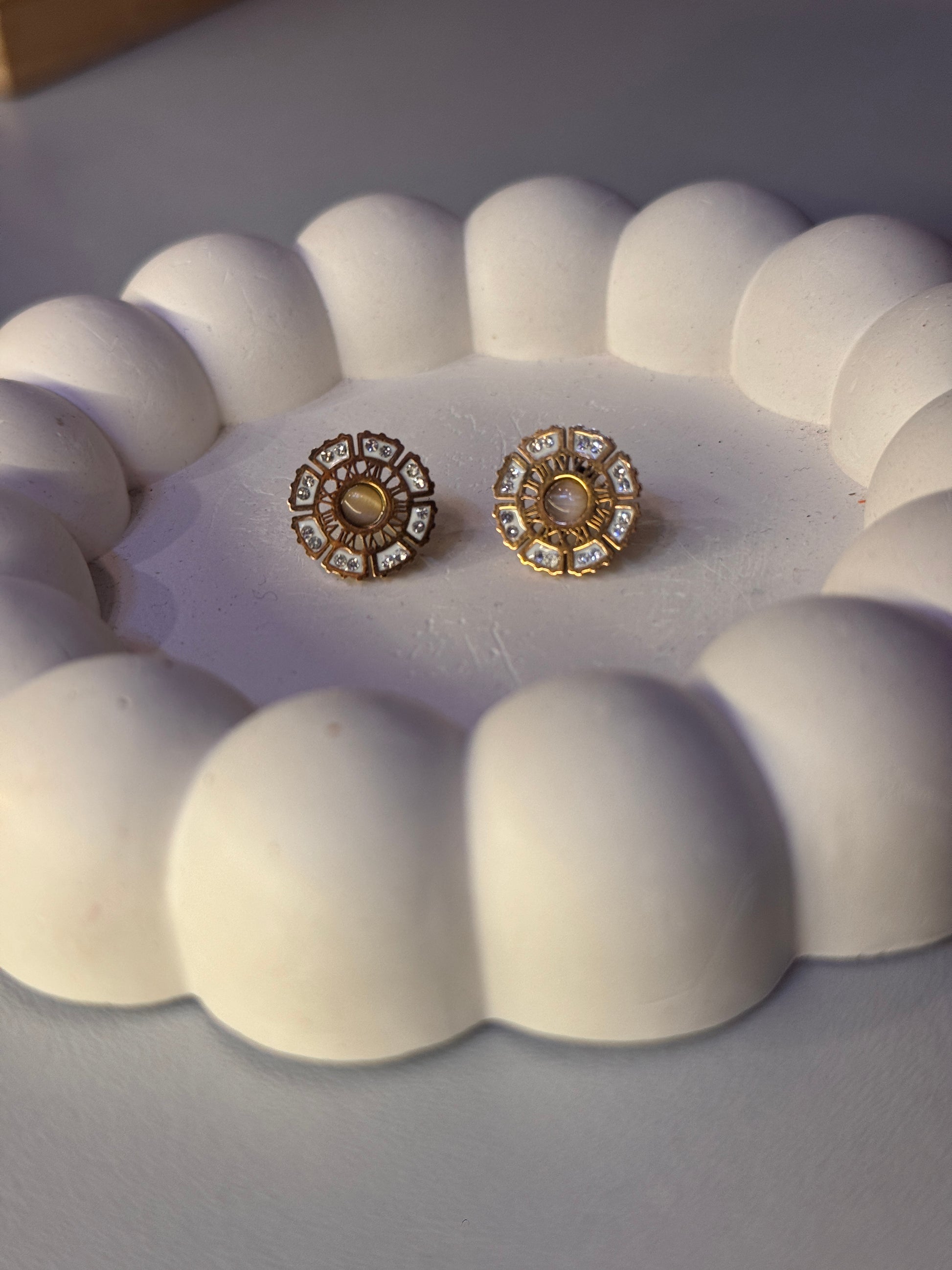 Pair of gold and diamond earrings on a white textured surface