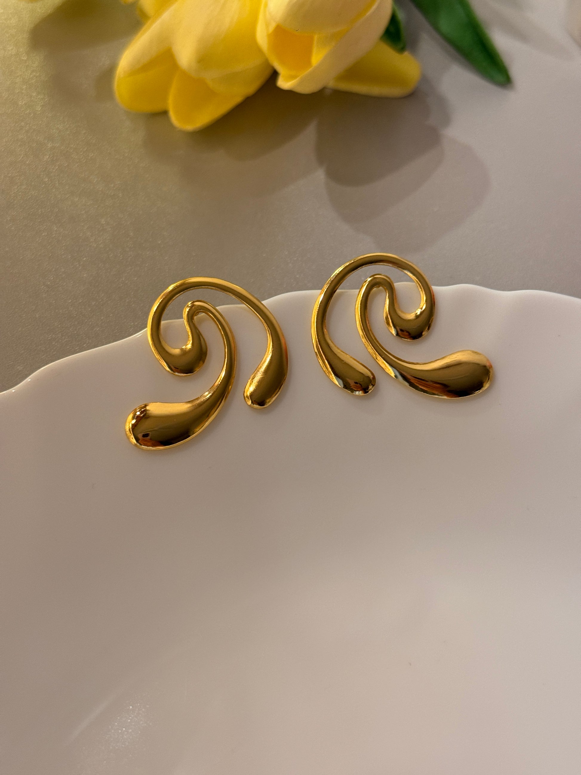 Gold decorative elements on a white plate with a yellow flower.