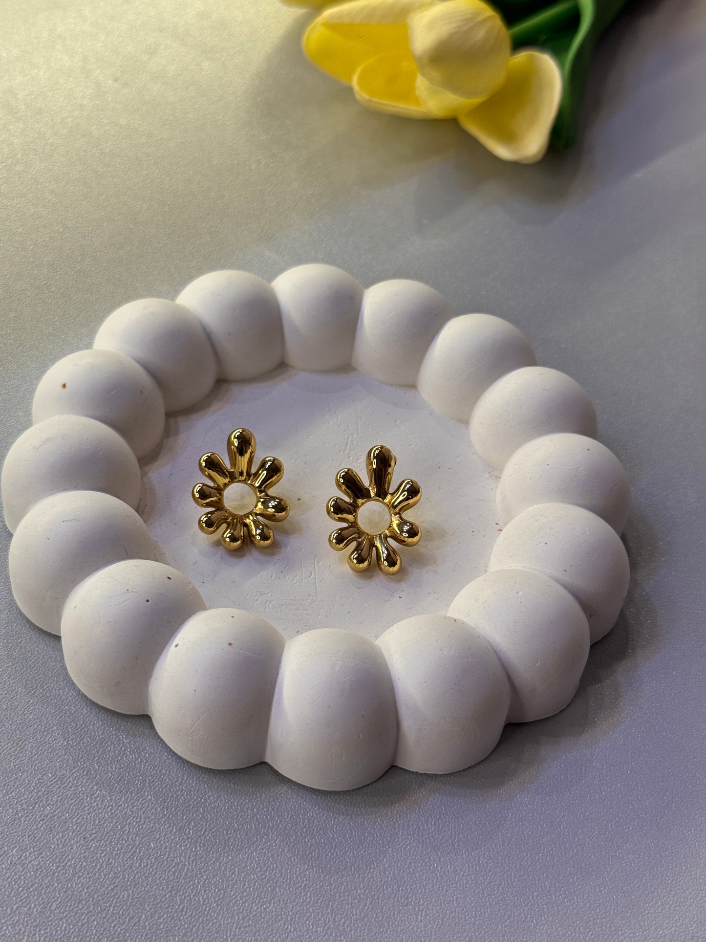 White beaded bracelet with gold flower-shaped clasps on a light gray background
