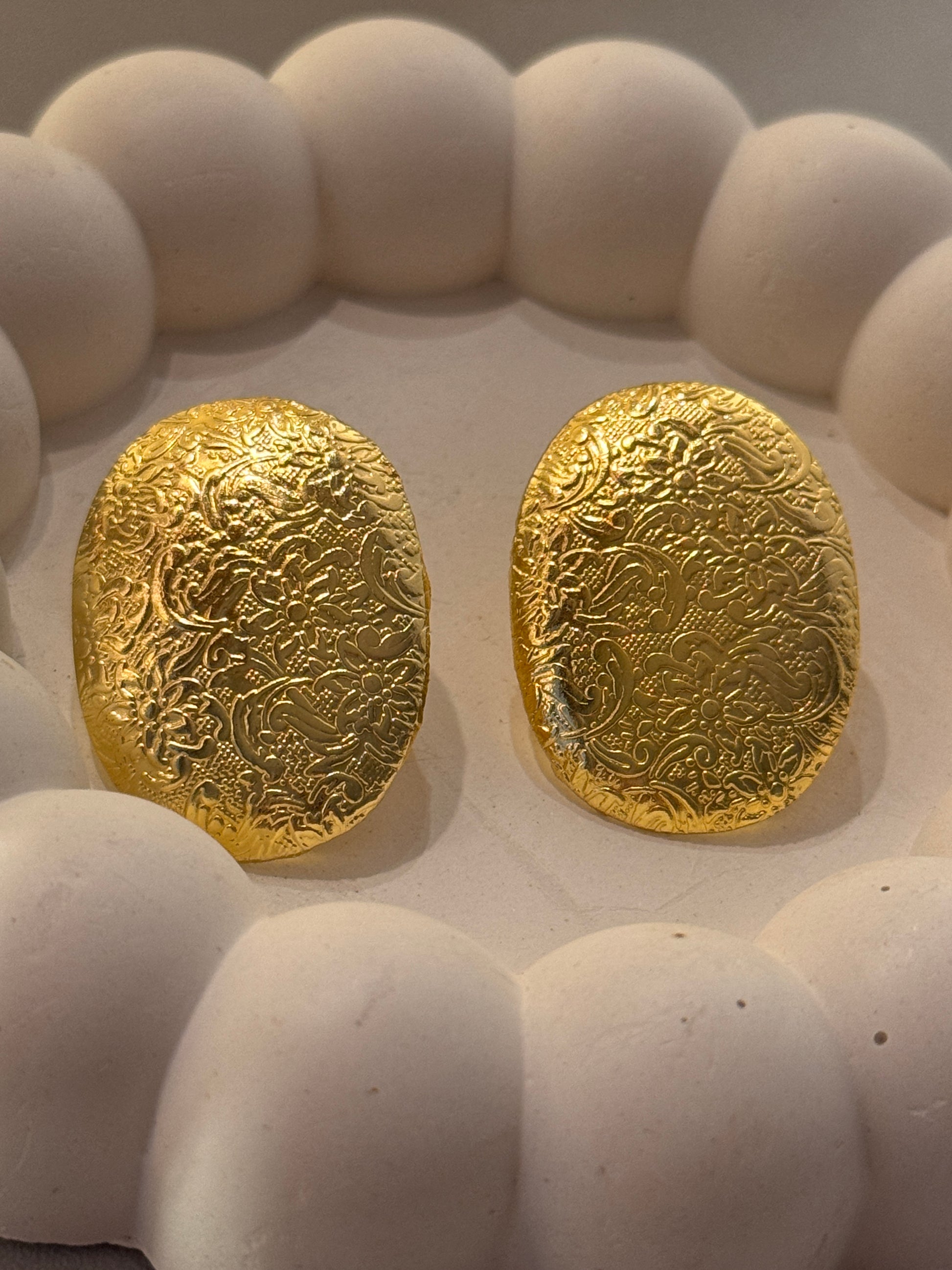Two gold stones with intricate patterns on a white stone surface