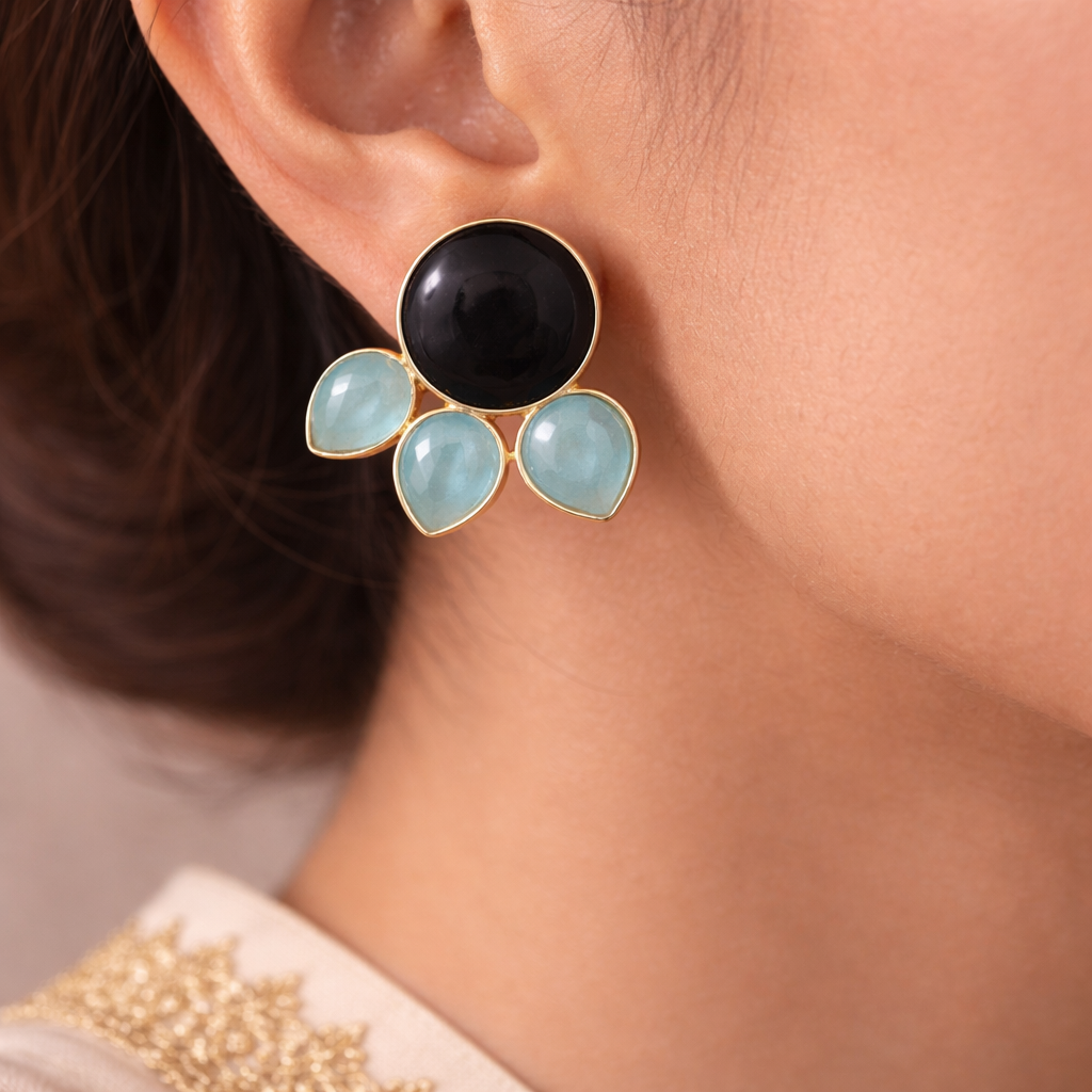 Close-up of an earring with black and light blue stones on a person's ear.