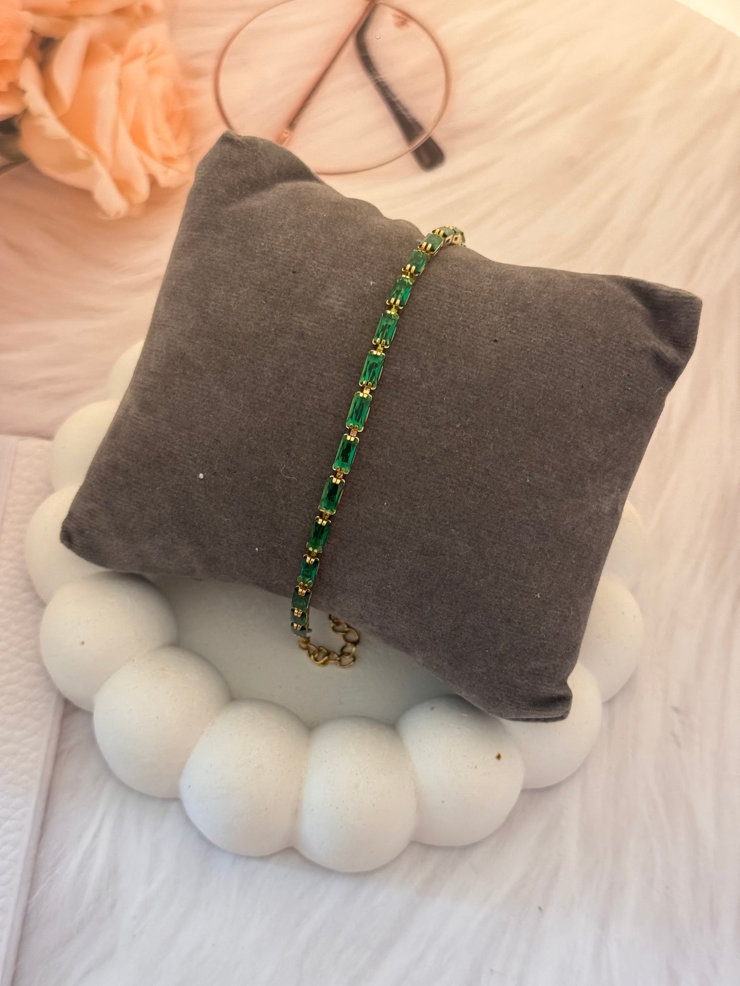 Green beaded bracelet on a gray pillow with a blurred background