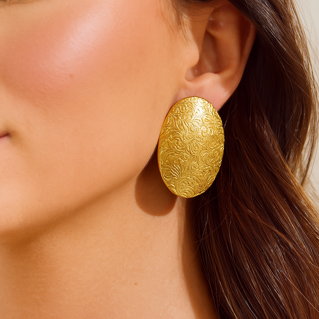 Gold earrings being worn on a model's ear