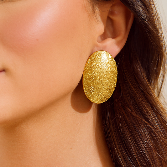 Gold earrings being worn on a model's ear
