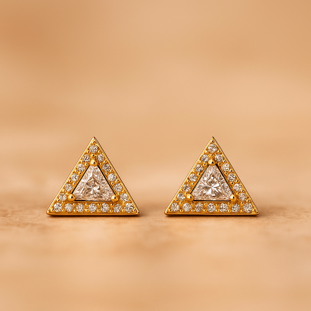 Pair of triangular gold earrings with diamond accents on a beige background
