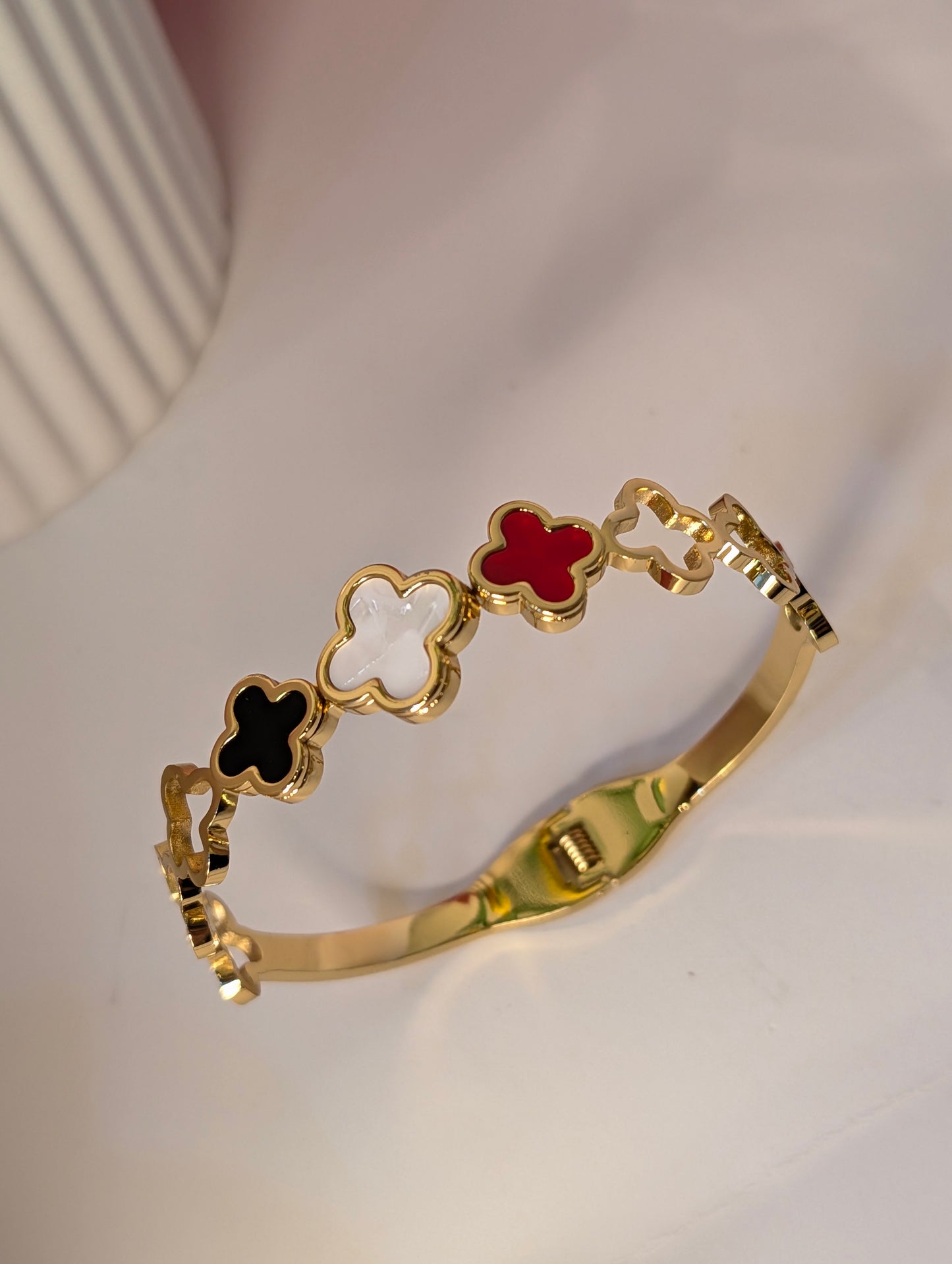 Gold bracelet with colorful clover-shaped charms on a white background